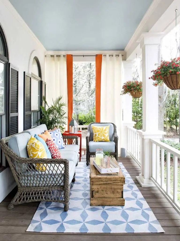 A styled front porch with planters, a doormat, and seating